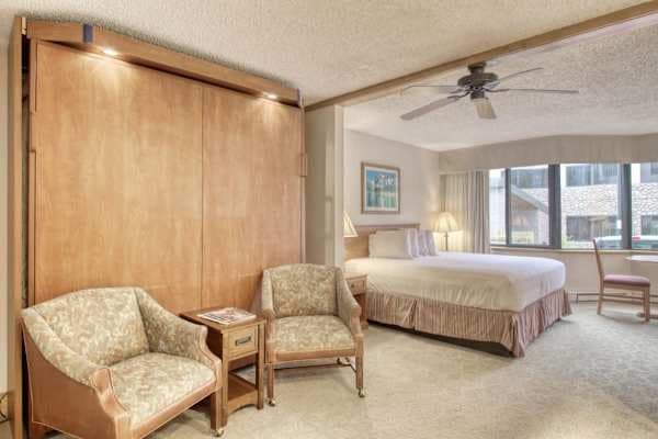 【King Murphy Bed】Folds down from the wood-paneled wall — sleeps 4 when you need it, hidden when you don't.