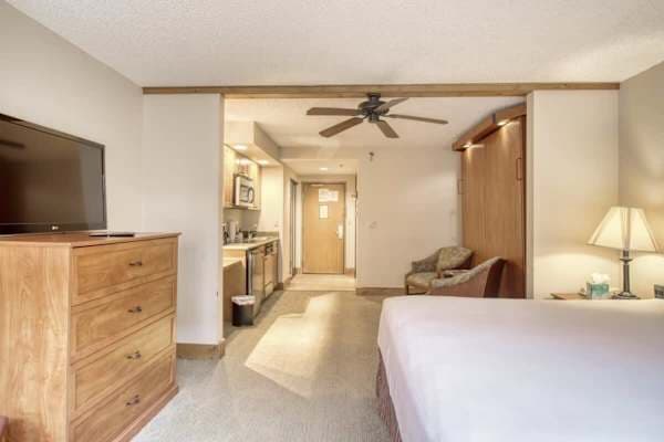 【From the Bed】Looking back toward the kitchenette, sitting chairs, and front door — full first-floor layout.