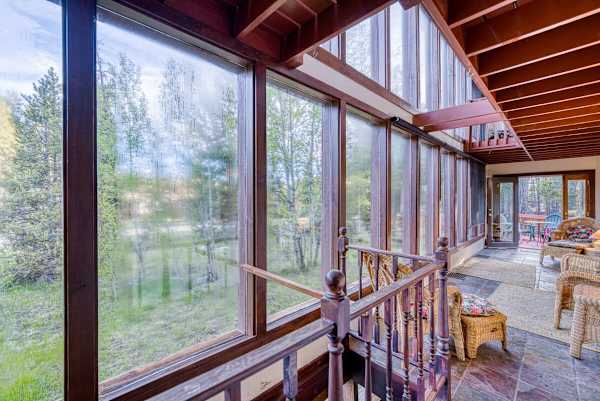 a sunroom or enclosed porch with large windows overlooking a wooded area