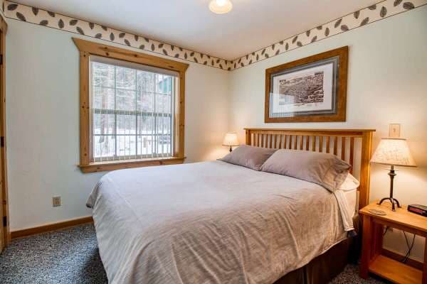 【Primary Bedroom】Queen bed on the main floor — blackout curtains for dawn patrol ski alarms.