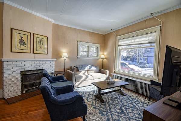 【Living Room】 Wood-burning fireplace and blue-velvet armchairs — 1880s parlor warmth for a 20°F Leadville morning.
