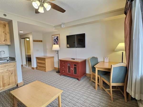 Cozy living area with kitchenette, dining for two, TV, and ceiling fan. | Listed with @BookTraverse
