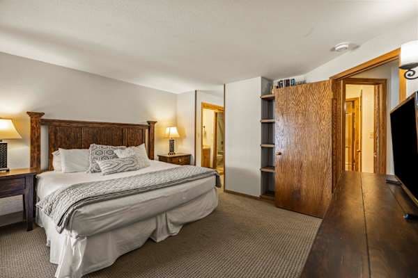 【Bedroom 1 — Primary King】King under wood-beam ceiling — the quiet end of the condo